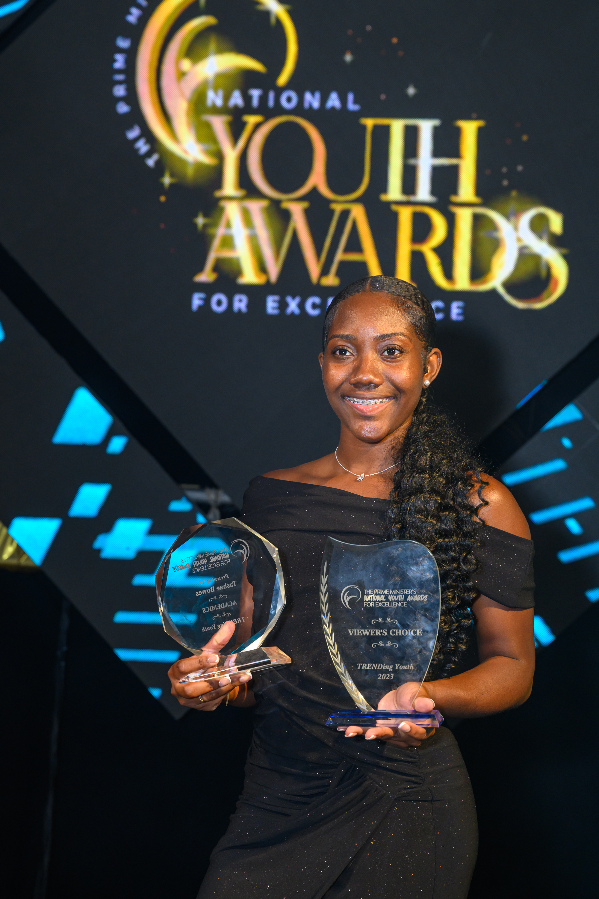 Tashae Bowes holds two awards and smiles.